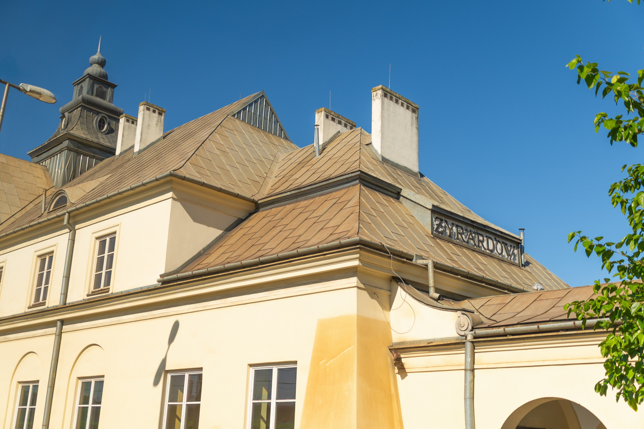 Historic building with tan roof against clear blue sky. Żyrardów railway station. Żyrardów, Poland.